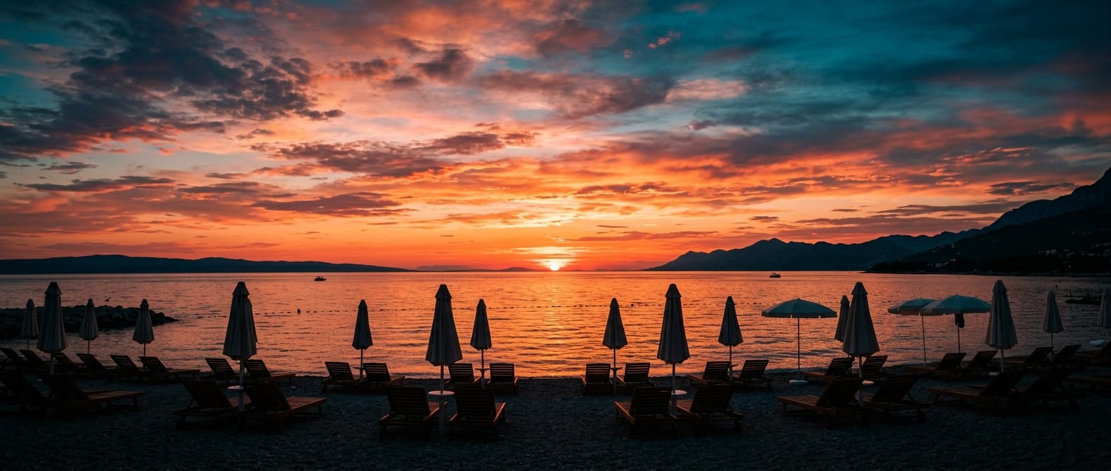 Wide cinematic view of the sun setting over the Adriatic sea behind rows of beach umbrellas
